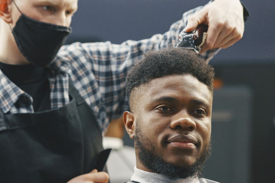 Barbeiro fazendo o corte na cadeira
